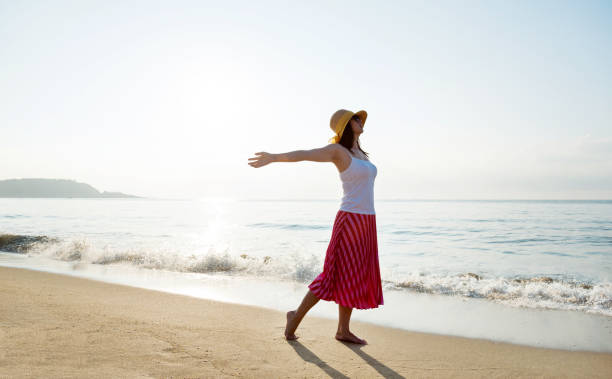 istock Young woman standing on beach with arms outstretched 1065814508