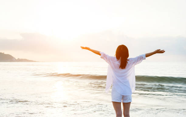 istock Young woman standing on beach with arms raised 1065814514