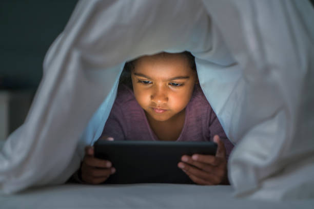 istock Girl watching movie on digital tablet under sheet 1065814772