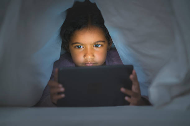 istock Cute girl watching digital tablet under blanket 1065814902