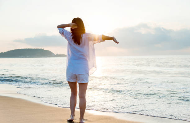 istock Young woman standing on beach with arms outstretched 1065816884