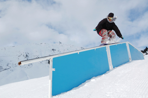young snowboarder riding on jibbing handrail