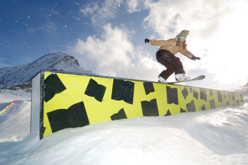 young snowboarder woman riding on jibbing box 