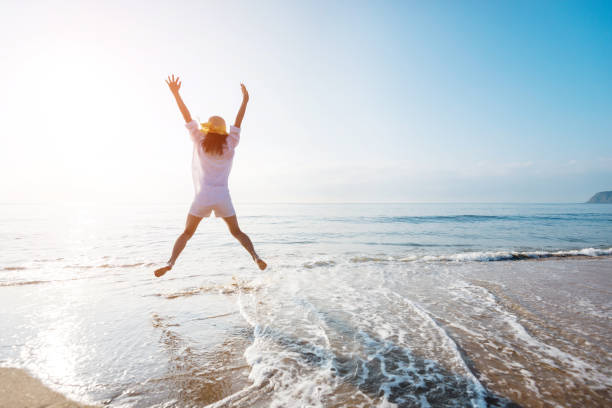 istock Excited woman jumping at the beach 1065822312