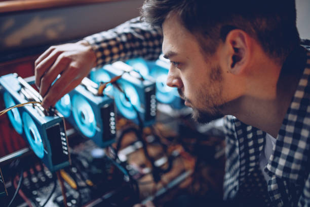 Young programmer preparing mining rig Programmer preparing mining rig for cryptocurrency mining cryptocurrency mining stock pictures, royalty-free photos & images