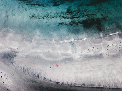 Drone photo of man, woman and dog staying near northern sea at stunning beach on Senja island in Norway