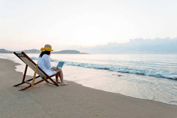 istock Woman using laptop at the beach 1065824402
