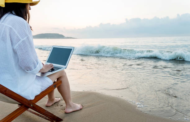 istock Woman using laptop at the beach 1065824428