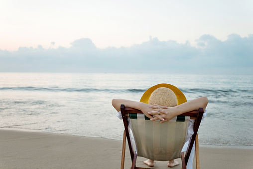 Woman relaxing on deck chair at the beach.