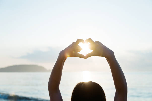 istock Woman hand making heart shape around the sun 1065824540