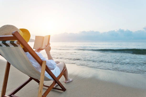 istock Woman reading book at the beach 1065824614