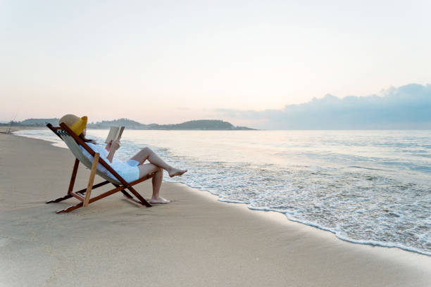 istock Woman reading book at the beach 1065824634