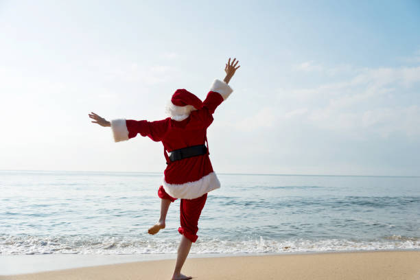 istock Santa Claus standing on sea beach with arms raised 1065827048
