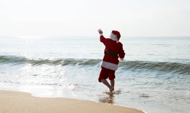 Santa Claus running on sea beach.