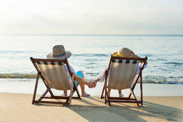 istock Couple sitting on deck chair at beach 1065828092