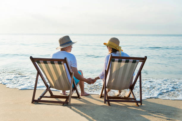 istock Couple sitting on deck chair at beach 1065828160