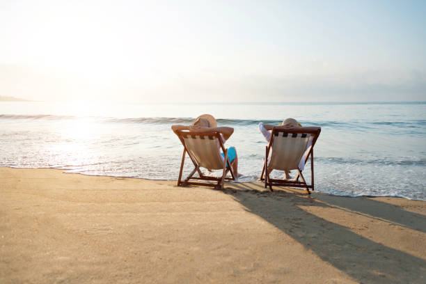 istock Couple sitting on deck chair at beach 1065828162