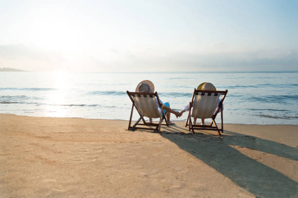 istock Couple sitting on deck chair at beach 1065829224