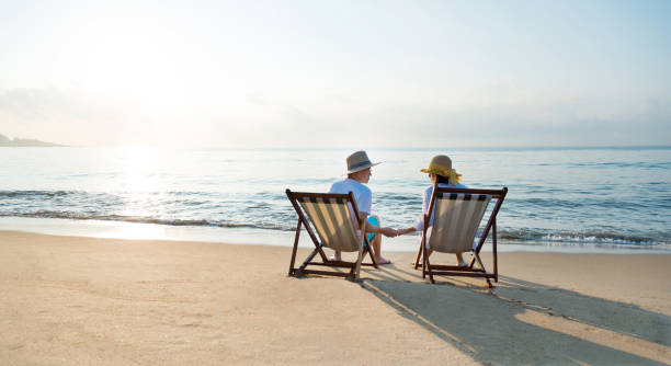 istock Couple sitting on deck chair at beach 1065829232