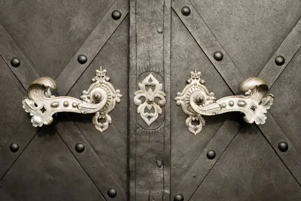 Closeup of a beautiful old doorhandles and decoration made of silver on a dark door