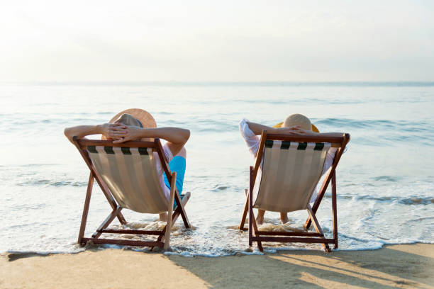 istock Couple sitting on deck chair at beach 1065829290