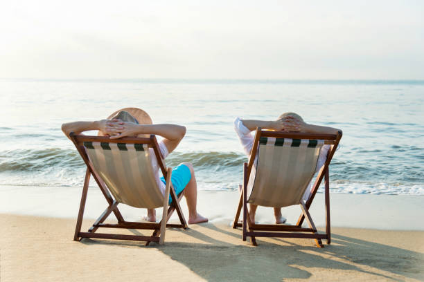 istock Couple sitting on deck chair at beach 1065829298