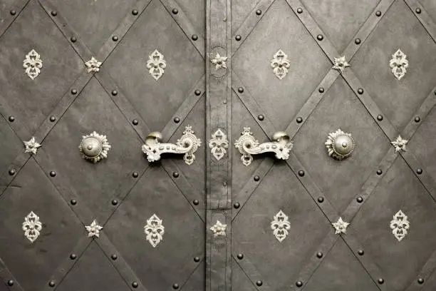 Closeup of a beautiful old doorhandles and decoration made of silver on a dark door