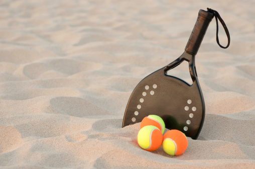 Raqueta de tenis en la playa de arena photo