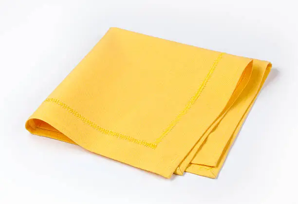 Photo of Isolated yellow napkin twice folded on white background