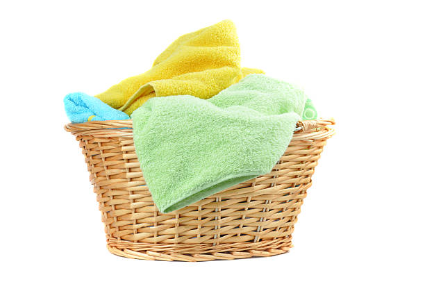 A wicker basket with colorful towels isolated on white