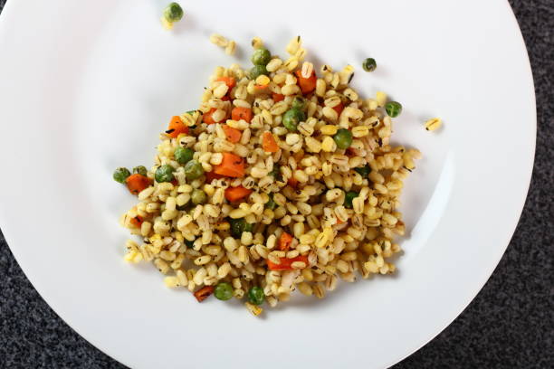 istock Cooked pearl barley with carrot and green peas on plate 1065852174