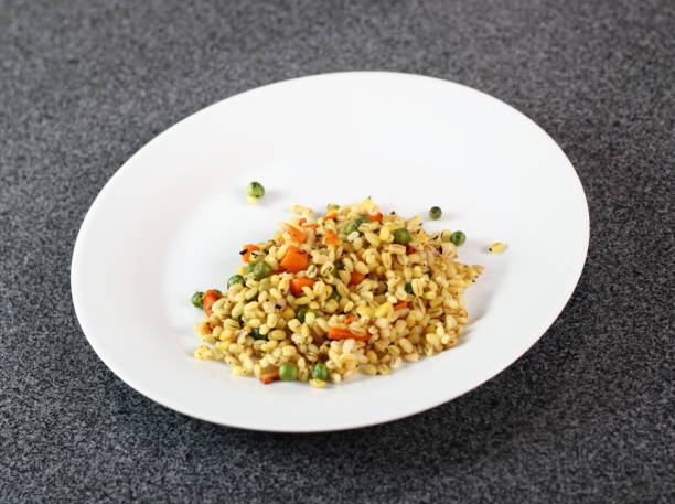 istock Cooked pearl barley with carrot and green peas on plate 1065853264