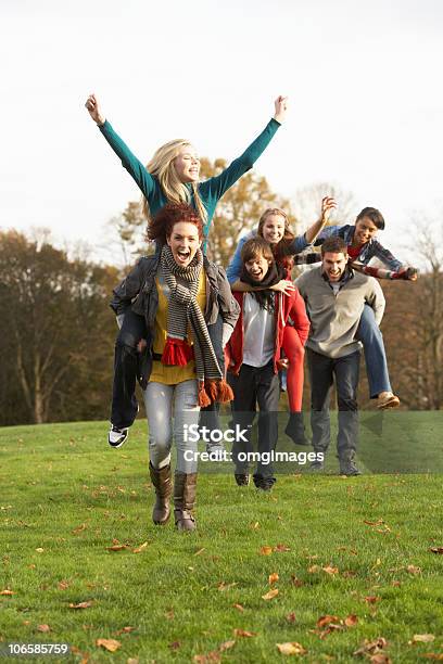 Teenage Amigos Teniendo Paseos Superpuesto En Otoño Paisaje Foto de stock y más banco de imágenes de Amistad