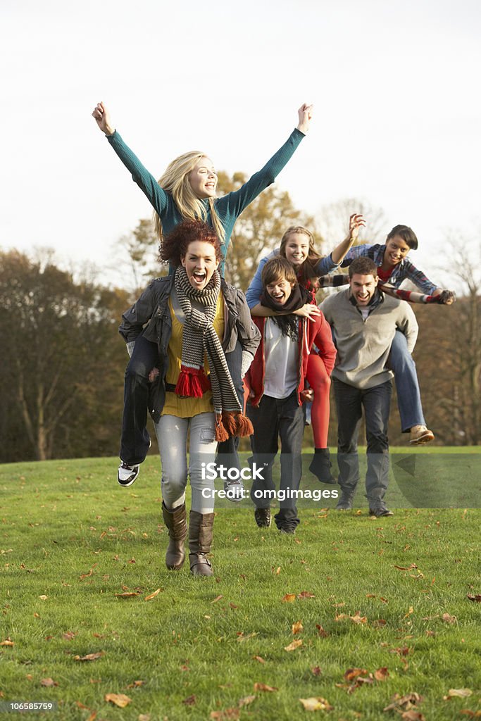 Amici adolescenti con giostre Piggyback In autunno paesaggio - Foto stock royalty-free di Amicizia