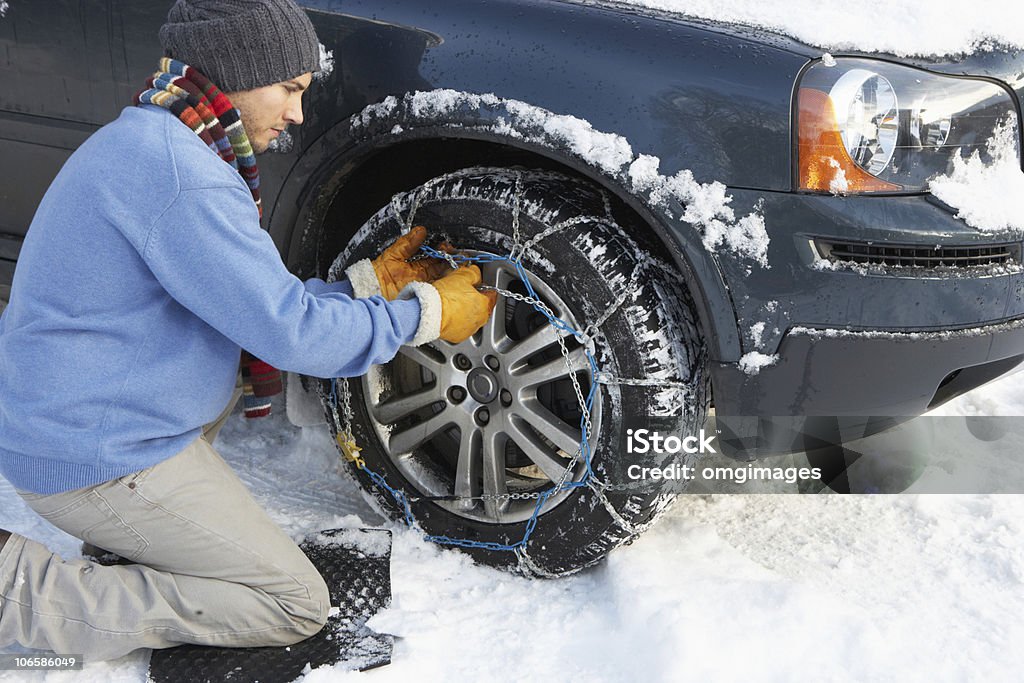 Mann Putting Schnee Ketten auf die Reifen des Autos. - Lizenzfrei Schneekette Stock-Foto