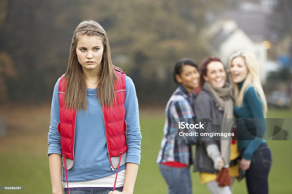 Upset Teenage Girl With Friends Gossiping In Background  Teenage Girls Stock Photo