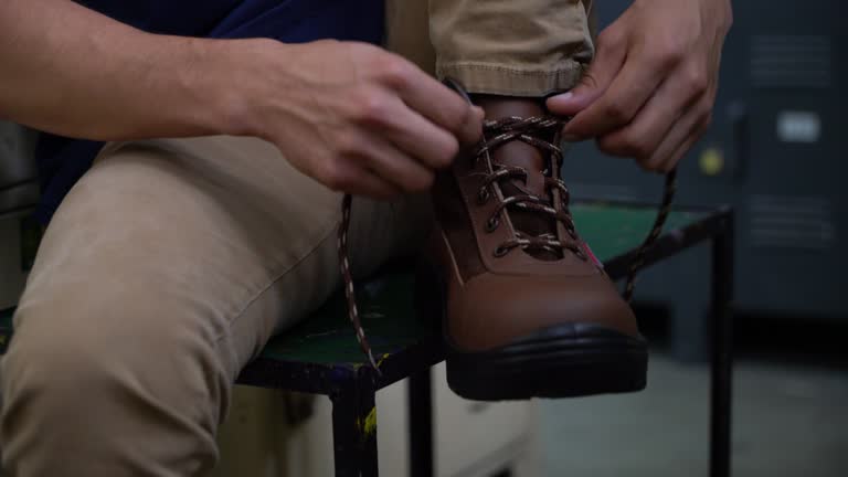 Close up of unrecognizable man putting on his working boots and trying them