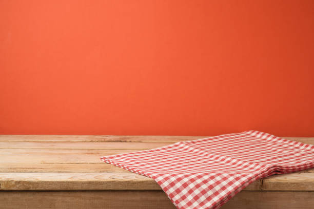 istock Empty wooden table with red checked tablecloth over red wall  background 1065864168