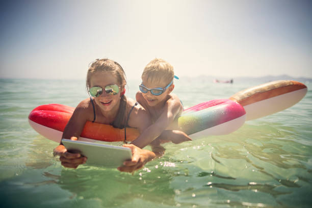 istock Kids enjoying using waterproof tablet during beach holiday 1065874104