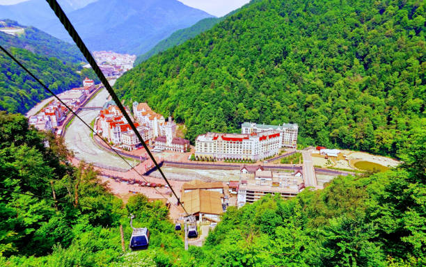 vista vibrante de sol teleférico carretera en sochi en rosa khutor bajo cielo azul con verde bosque - overhead cable car summer ski lift scenics fotografías e imágenes de stock