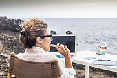 freedom and lifestyle for young woman at work in front of the ocean with no rooms and offices. laptop open and lady thinking at his career and his life. enjoying freedom and alternative work concept