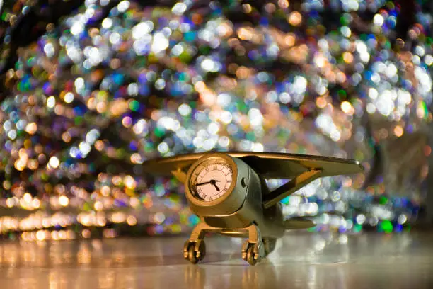 Studio still-life photograph of a small silver airplane showpiece containing a clock