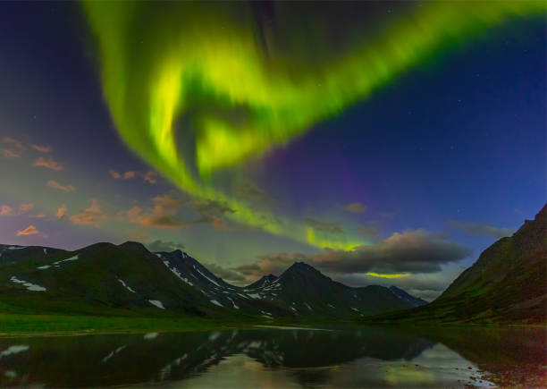 istock Aurora in the night sky cut the mountains, reflected in the water 1065879246