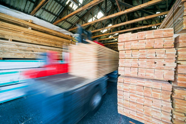 Forklift and stacked wooden planks in warehouse stock photo