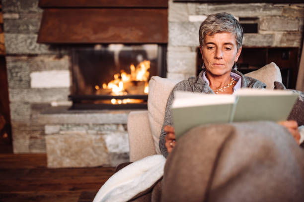 istock woman reading a book at home in winter on the sofa 1065885384
