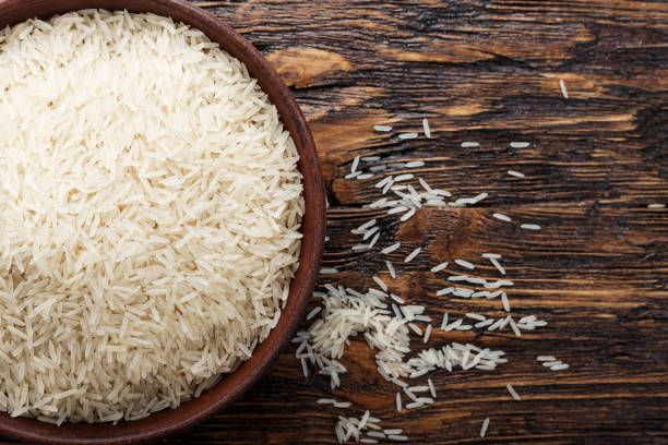 istock raw rice in a plate on wooden background. place for text. 1065889514