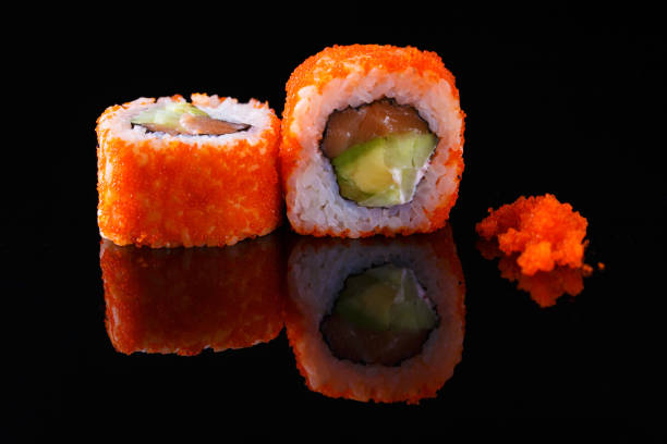 istock Appetizing sushi roll with fish and caviar, on a black background with reflection. Menu and restaurant concept. 1065892732
