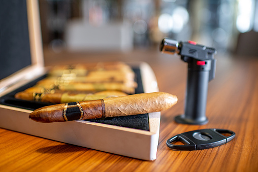 Close-up of luxury cigar set with lighter on the wooden table indoors