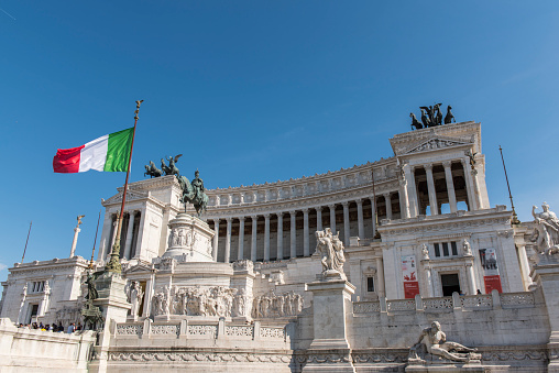 People walking next to The Altare della Patria (Altar of the Fatherland). This huge neoclassical and eclectic monument was built in honor of Victor Emmanuel, was completed in 1925 and it is located between Piazza Venezia and the Palatine Hill, close to the Roman Forum.  It is visited daily by thousands of tourist from all over the world.