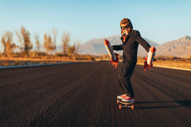 business-boy mit raketen auf skateboard stehen - taking off business creativity adventure stock-fotos und bilder